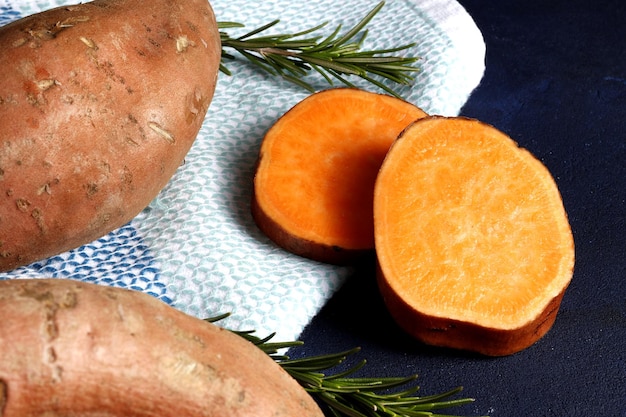 Composition of sweet potatoes, rosemary spices, on a dark background. Space for text.