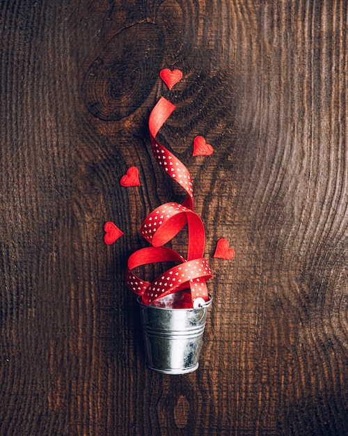 Composition of tissue hearts and decorative buckets on a dark wooden background