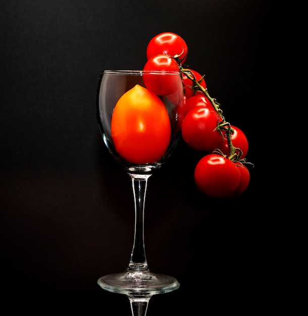 Composition of tomatoes of different sizes and colors in a wine glass. Natural product. Natural color. Close-up.