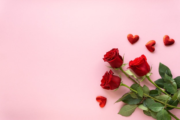 Composizione per san valentino. bouquet di rose rosse e cuori su sfondo rosa, copyspace