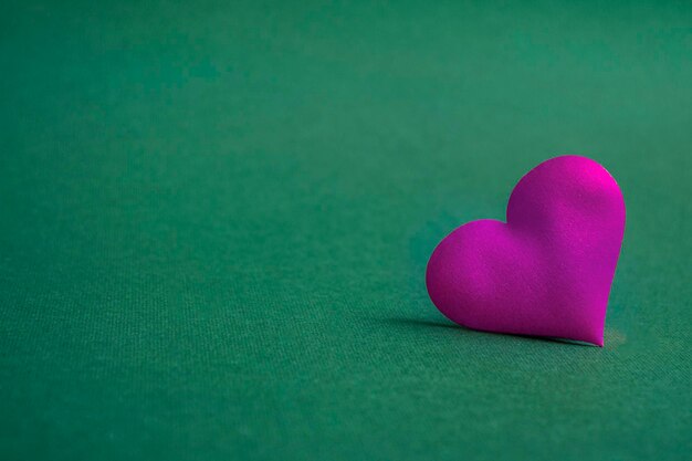 Composition for Valentine's Day. On a green background, pink hearts close up with copy space