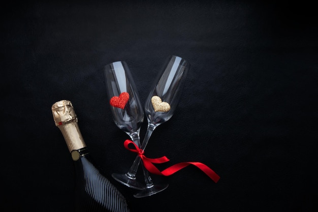 Composition for valentine's day with champagne glasses and hearts on a black background Flat lay