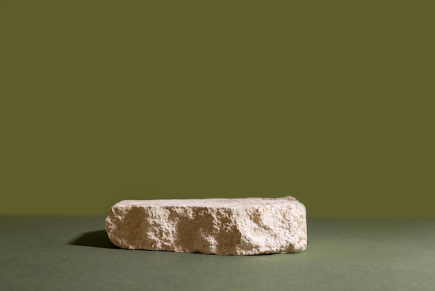 自然な有機化粧品のための緑の背景の抽象的な表彰台に白い石の組成...
