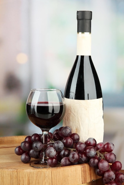 Композиция из стекла бутылки вина и деревянной бочки из винограда на ярком фоне