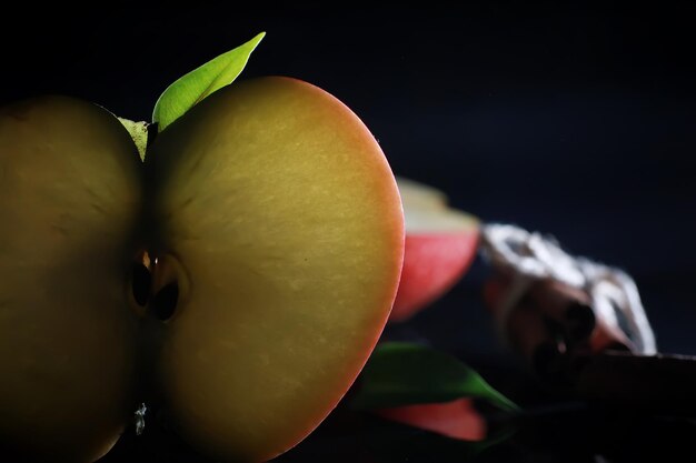 Composition with apple slices on a black background. A slice of apple with back light on a black background with water drops. Juicy apple on a table.