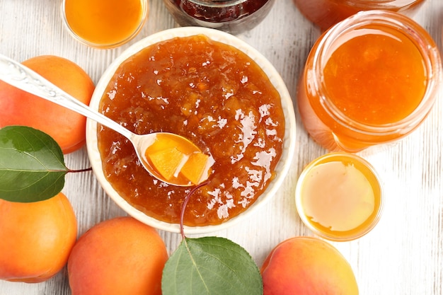 Composition with apricot jam and ripe juicy fruit on wooden table