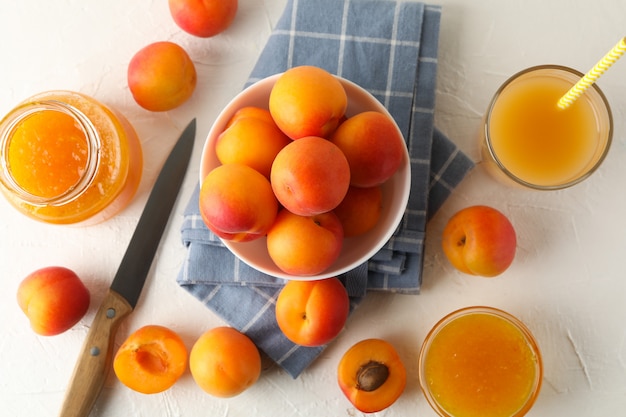 Composition with apricots, juice and jam on white table