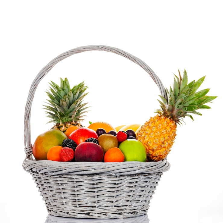 Photo composition with assorted fruits in wicker basket on white background
