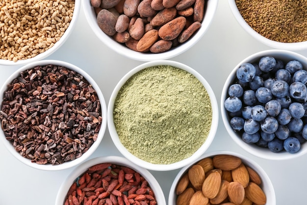 Composition with assortment of superfood products in bowls on white background closeup