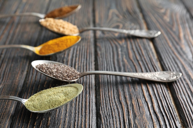 Photo composition with assortment of superfood products in spoons on wooden background