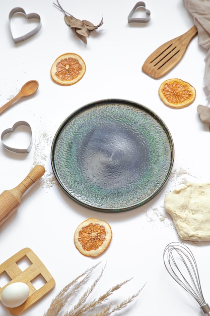 Composition with baking ingredients and kitchen accessories on a white table top view.