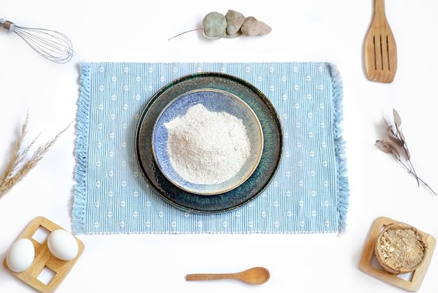 Composition with baking ingredients and kitchen accessories on a white table.