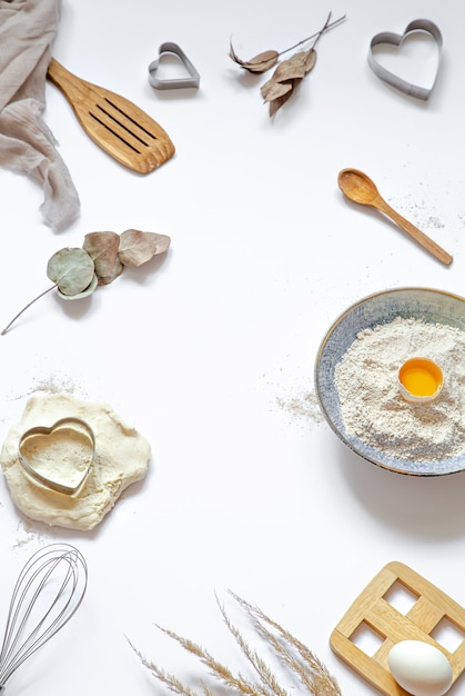 Composition with baking ingredients and kitchen accessories on a white table.