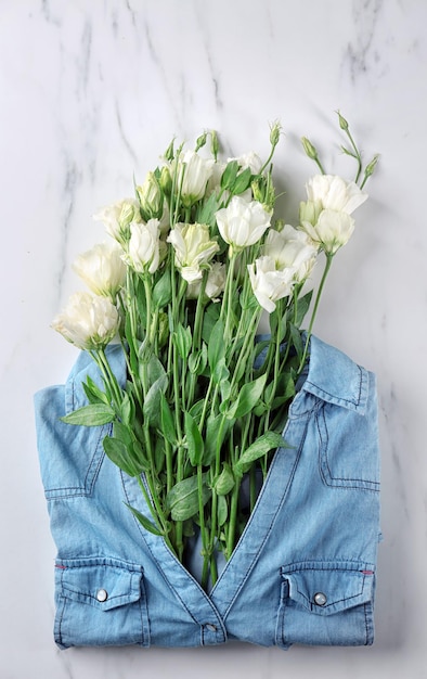 Composition with beautiful flowers in jeans shirt on light background