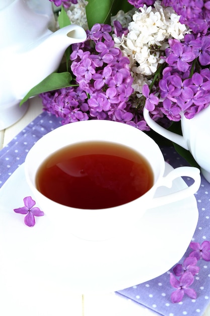 Composition with beautiful lilac flowers tea service on wooden table close up