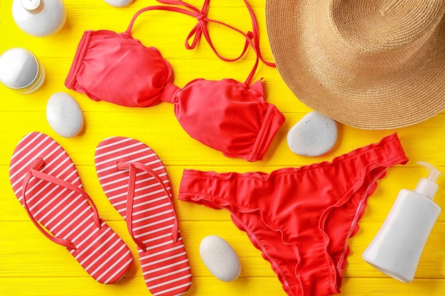 Composition with beautiful swimsuit on color wooden background