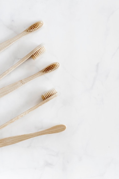 Composition with biodegradable bamboo toothbrushes on marble, flat lay