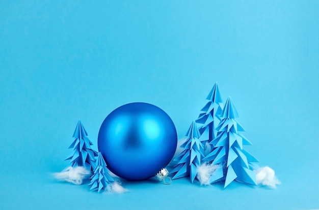 Composition with blue paper christmas trees and ball decoration