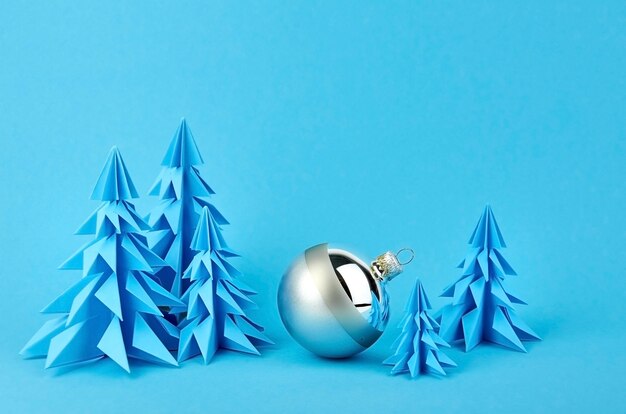 Photo composition with blue paper christmas trees and silver ball