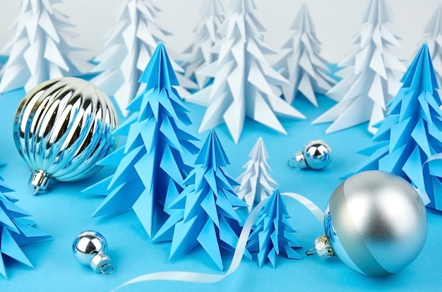 Composition with blue and white paper christmas trees and ball decorations