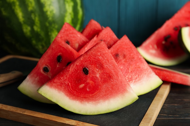 Composition with board with watermelon slices on wooden table