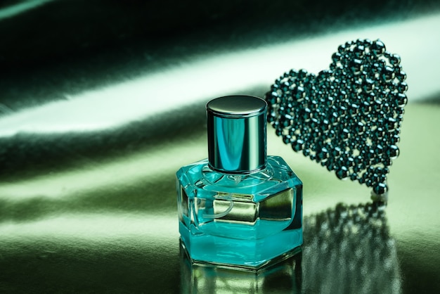 Composition with a bottle of perfume on a shiny turquoise background