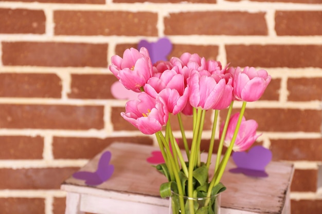 Composition with bouquet of tulips in vase, on ladder, on wall background