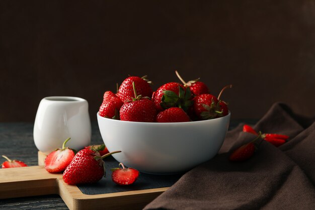 Composition with bowl of tasty strawberry on wooden table. Summer berry