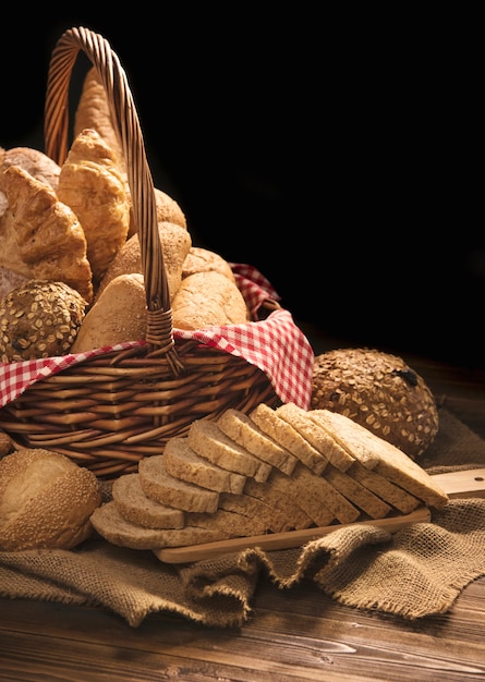 Composition with bread and rolls in wicker basket isolated on black