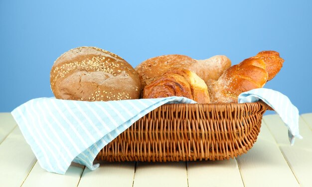 Composition with bread and rolls on wooden table on color background