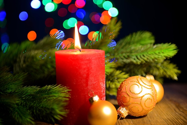 Композиция с горящей свечой, елкой и рождественскими украшениями на фоне разноцветных огней