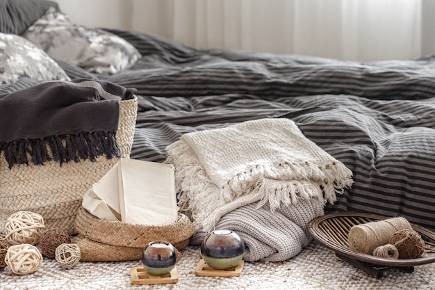 Composizione con candele, elementi in maglia e altri dettagli di arredo in camera da letto.