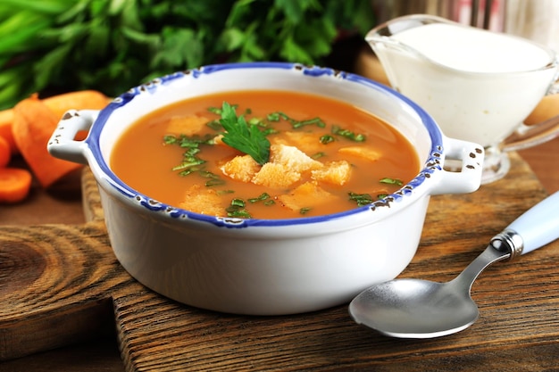 Composition with carrot soup ingredients and herbs on color wooden background