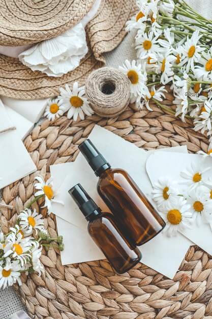 白い背景の上のビューにカモミールの花とエッセンシャル オイルの化粧品ボトルの組成物