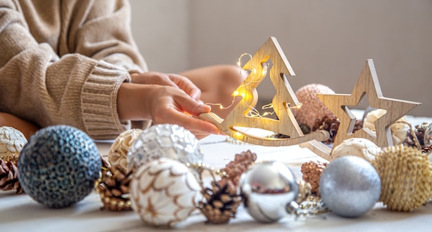 Composition with christmas decorations and female hands with wooden toy.