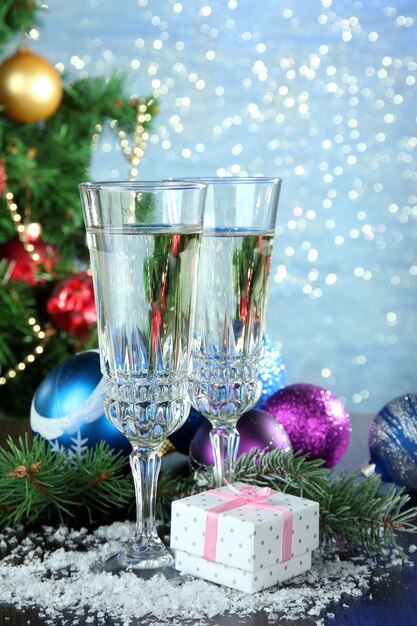 Composition with Christmas decorations and two champagne glasses on shiny blue