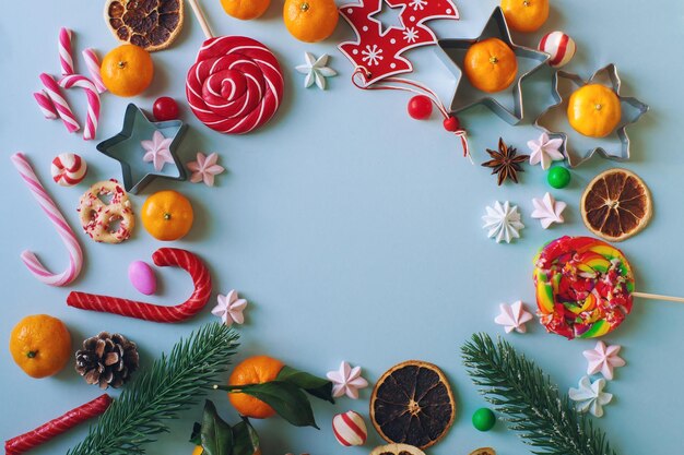 写真 クリスマス オブジェクト キャンディー杖モミの枝と明るい青の背景にみかんのコンポジション トップ ビュー コピー テキストのスペース