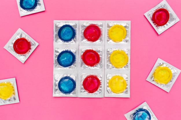 Composition with colorful condoms on bright pink background. Safe sex and contraceptive concept. Flat lay, top view.