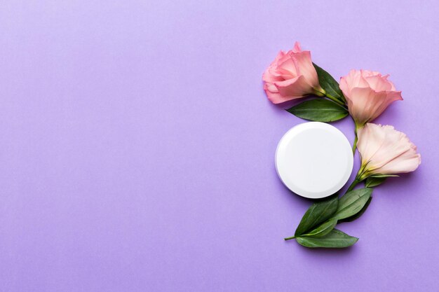 Composition with cosmetic products and beautiful roses on color background. Copy space, flat lay