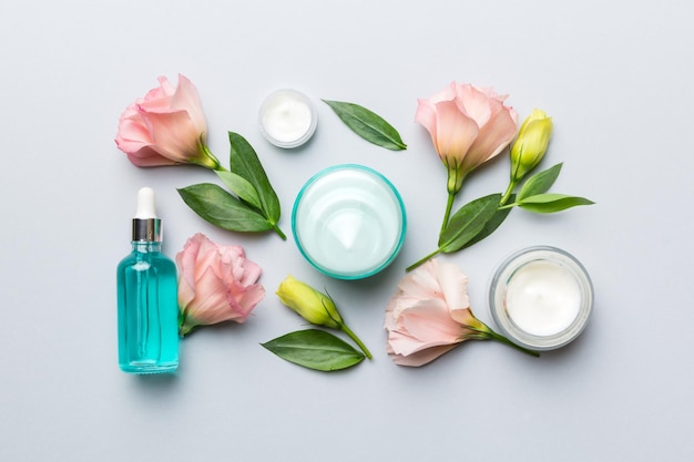 Composition with cosmetic products and beautiful roses on color background Flat lay