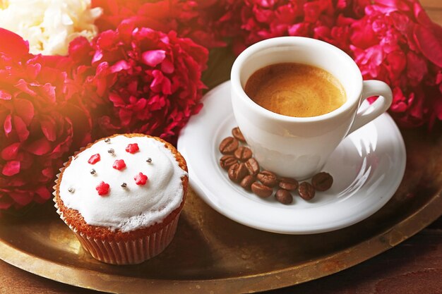 Composition with cup of coffee muffins and peony flowers on tray on wooden background