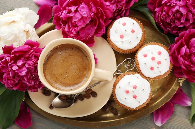 Composition with cup of coffee muffins and peony flowers on wooden background