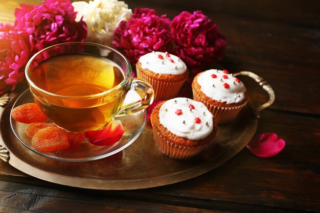 Composition with cup of herbal tea dried apricots and peony flowers on wooden background