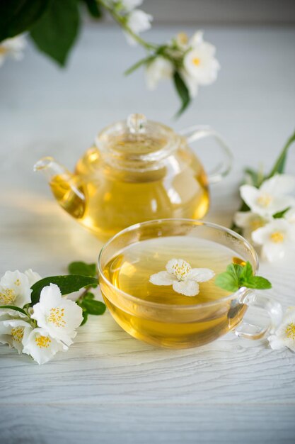 Composition with cup of jasmine tea and flowers on light background