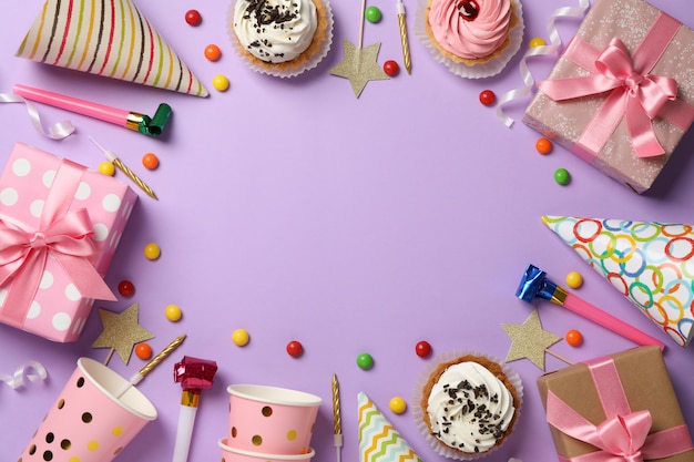 Composition with different birthday accessories on violet background, space for text