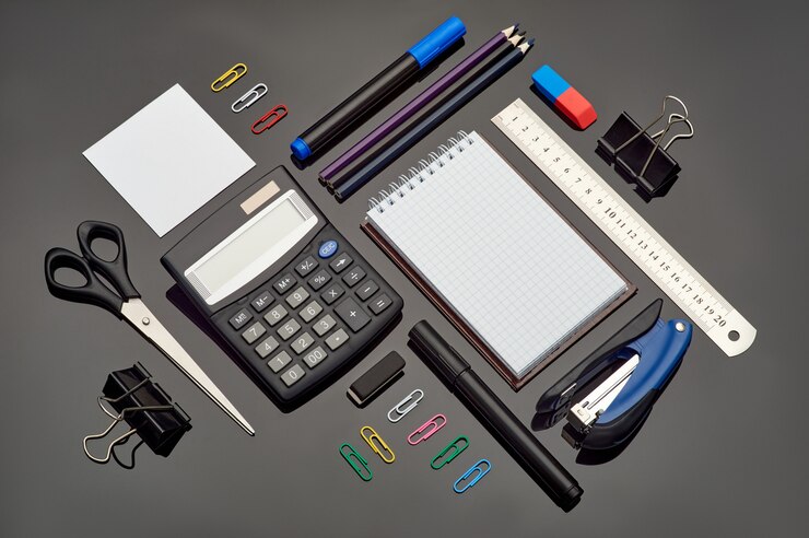 Photo composition with different school stationery and calculator on glass