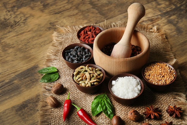 Composition with different spices and mortar on wooden background