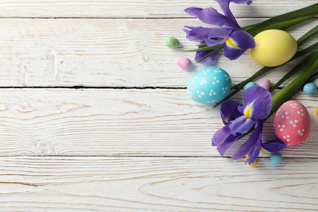 Композиция с пасхальными яйцами и цветами ириса на деревянной поверхности