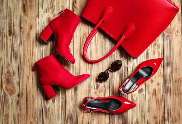 Composition with female stylish shoes and bag on wooden background