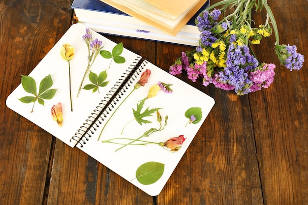木製の背景にノートに花と乾燥した植物のコンポジション